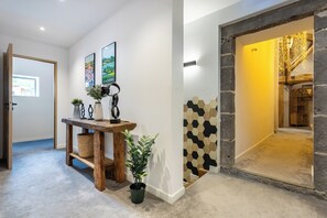 A hallway with a wooden bench, potted plants, and a wall with hexagonal tiles. - Renovated, spacious and comfortable 26-bed mill (Saint-Ignat)