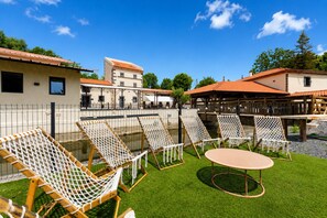 Un patio con mobiliario exterior, incluyendo sillas y una mesa, rodeado por una cerca.