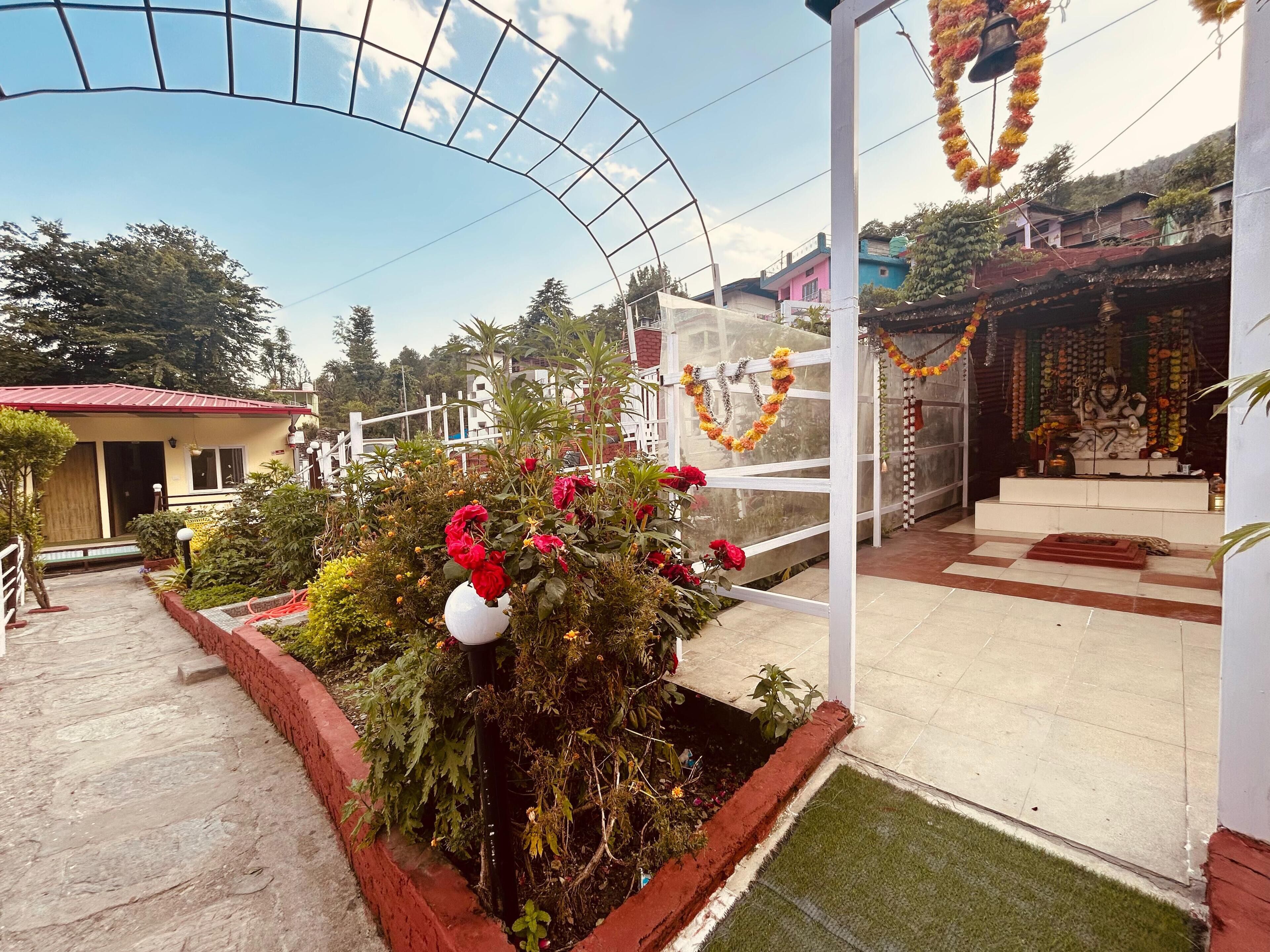 A temple with a white entrance, surrounded by lush greenery and red flowers.