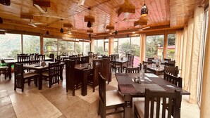 A spacious restaurant with wooden interior and large windows offering views of the outdoors.