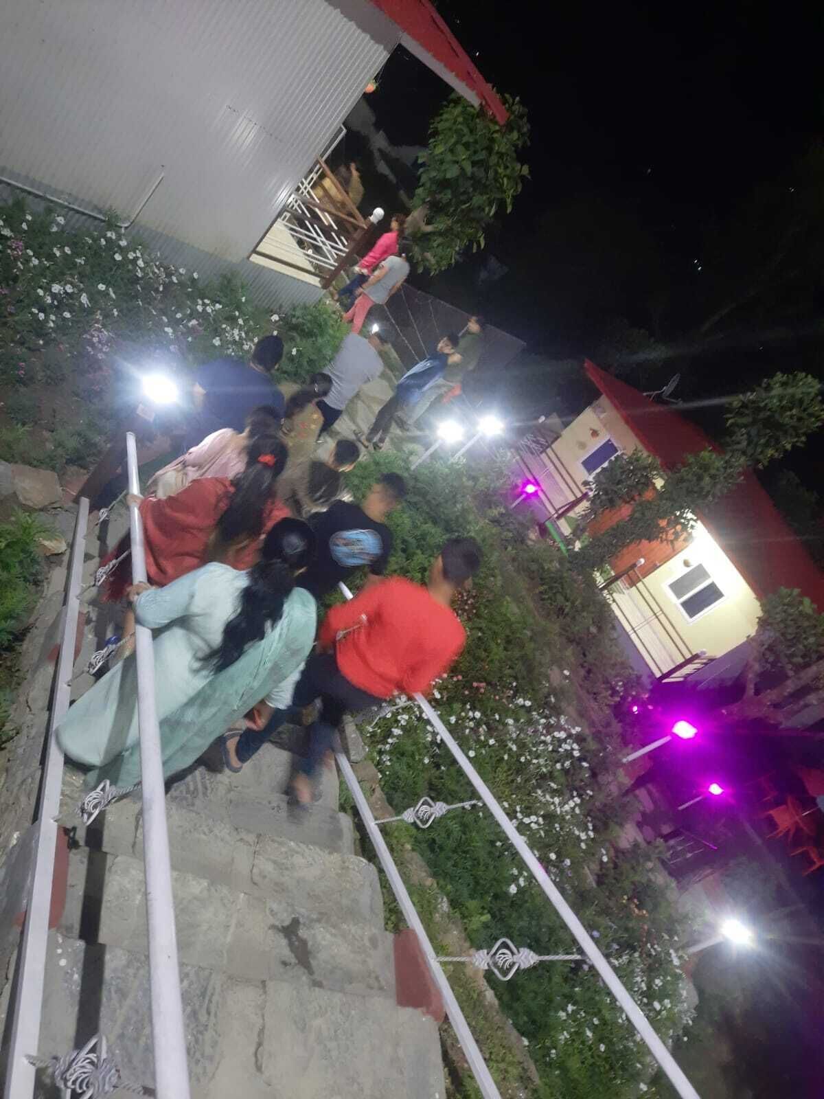 A group of people ascending a staircase at night, surrounded by greenery and illuminated by artificial lights.