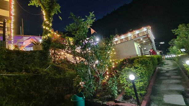 A pathway leading to a building with string lights and a well-maintained garden.