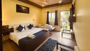 A hotel room with two beds, a ceiling fan, a painting on the wall, a window with curtains, and a TV mounted on the wall.