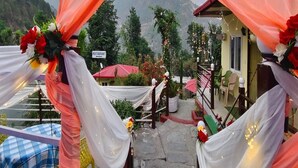 A restaurant with a mountain backdrop, decorated with drapes and flowers.