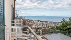 Ein Balkon mit Blick auf eine Küstenstadt, darunter Gebäude und das Meer.