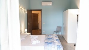 Ein Hotelzimmer mit Bett, Stuhl, Schreibtisch, Klimaanlage und Lampe.
