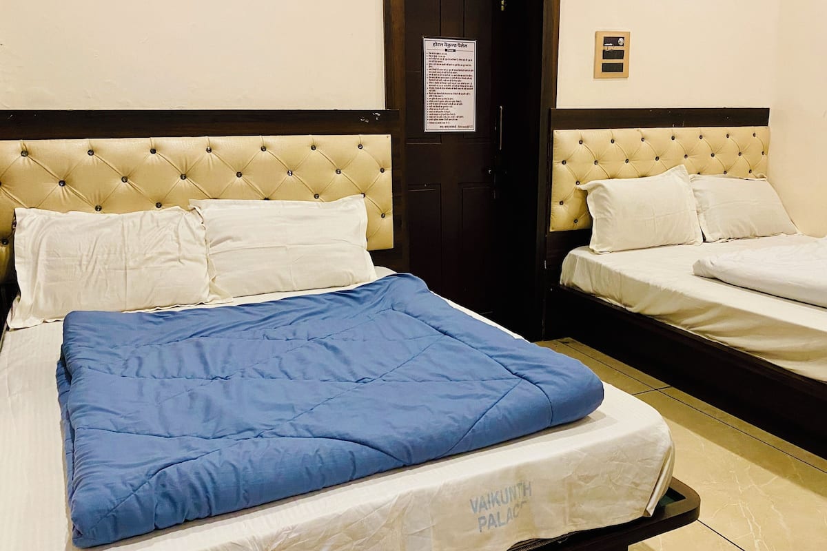 A hotel room with two beds, one with a blue blanket and the other with white bedding.