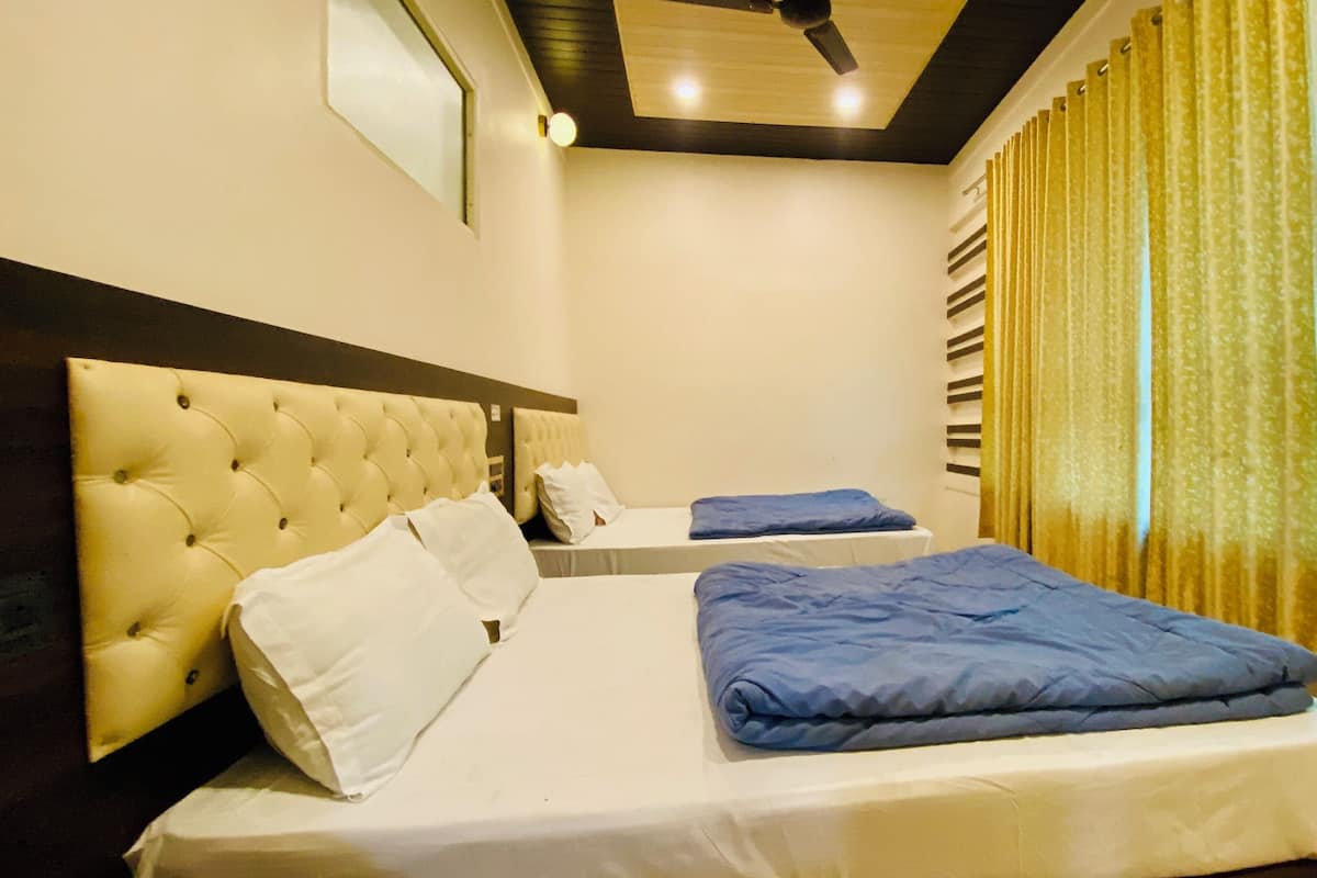 A hotel room with a large bed, a smaller bed, and a ceiling fan.