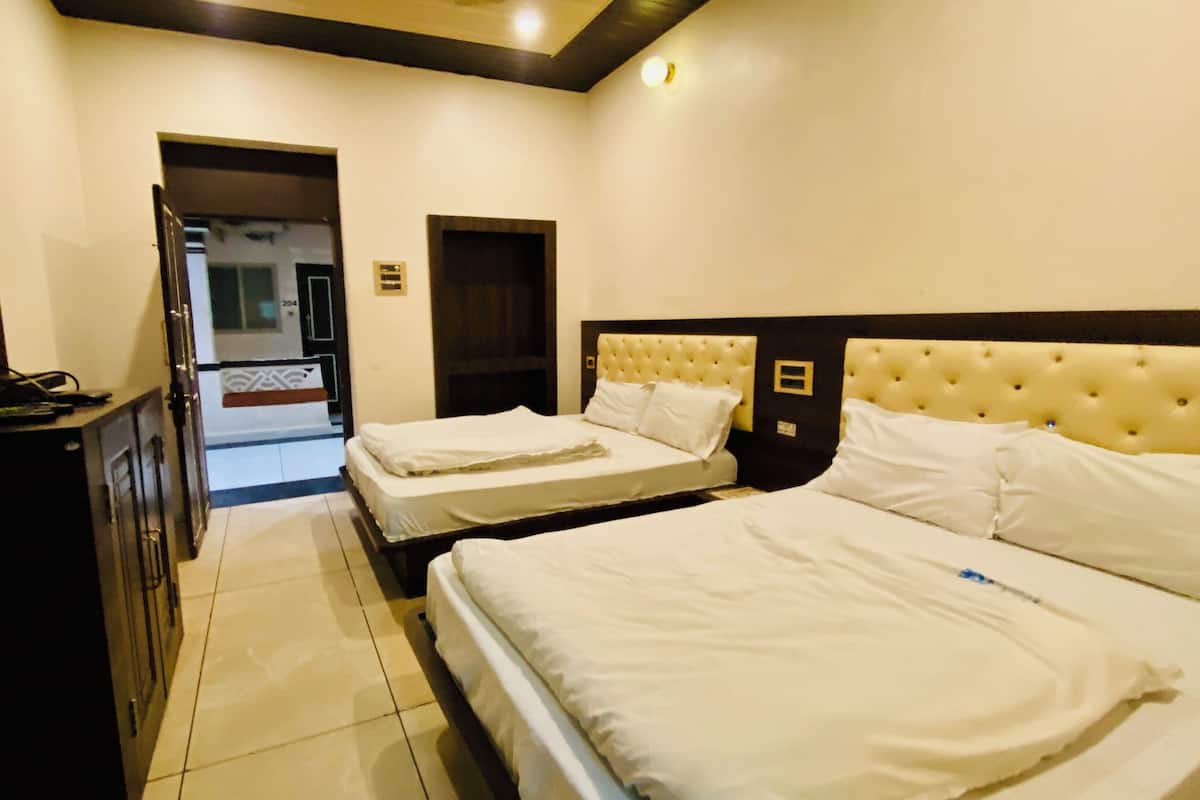 A hotel room with two beds, a television on the left, and a door leading to a hallway.