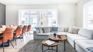 A modern living room with a dining area, a grey sofa, and a coffee table. - Elegant Coastal Retreat in Knokke-heist (Knokke-Heist)