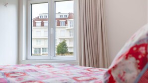 A bedroom with a bed, a window, and a view of a building outside. - Elegant Coastal Retreat in Knokke-heist (Knokke-Heist)