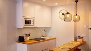Une cuisine compacte équipée d’un four à micro-ondes, d’un évier et d’un comptoir-bar en bois avec des tabourets.
