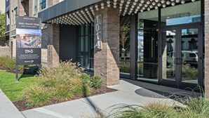 A modern building with a glass entrance and a sign advertising available properties.