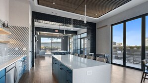 A modern kitchen with a large island, blue cabinets, and a view of the city through large windows.