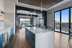 A modern kitchen with a large island, blue cabinets, and a view of the city through large windows.
