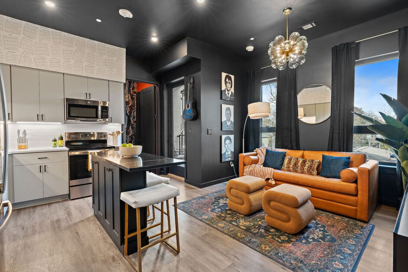 A modern kitchen with a central island, a sofa with cushions, and a large window with curtains.