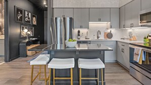 A modern kitchen with a central island, stainless steel appliances, and bar stools.