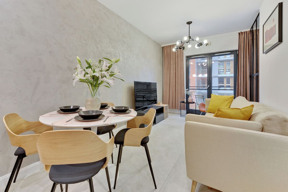 Una sala moderna con un sofá, una mesa de comedor, sillas y un televisor.