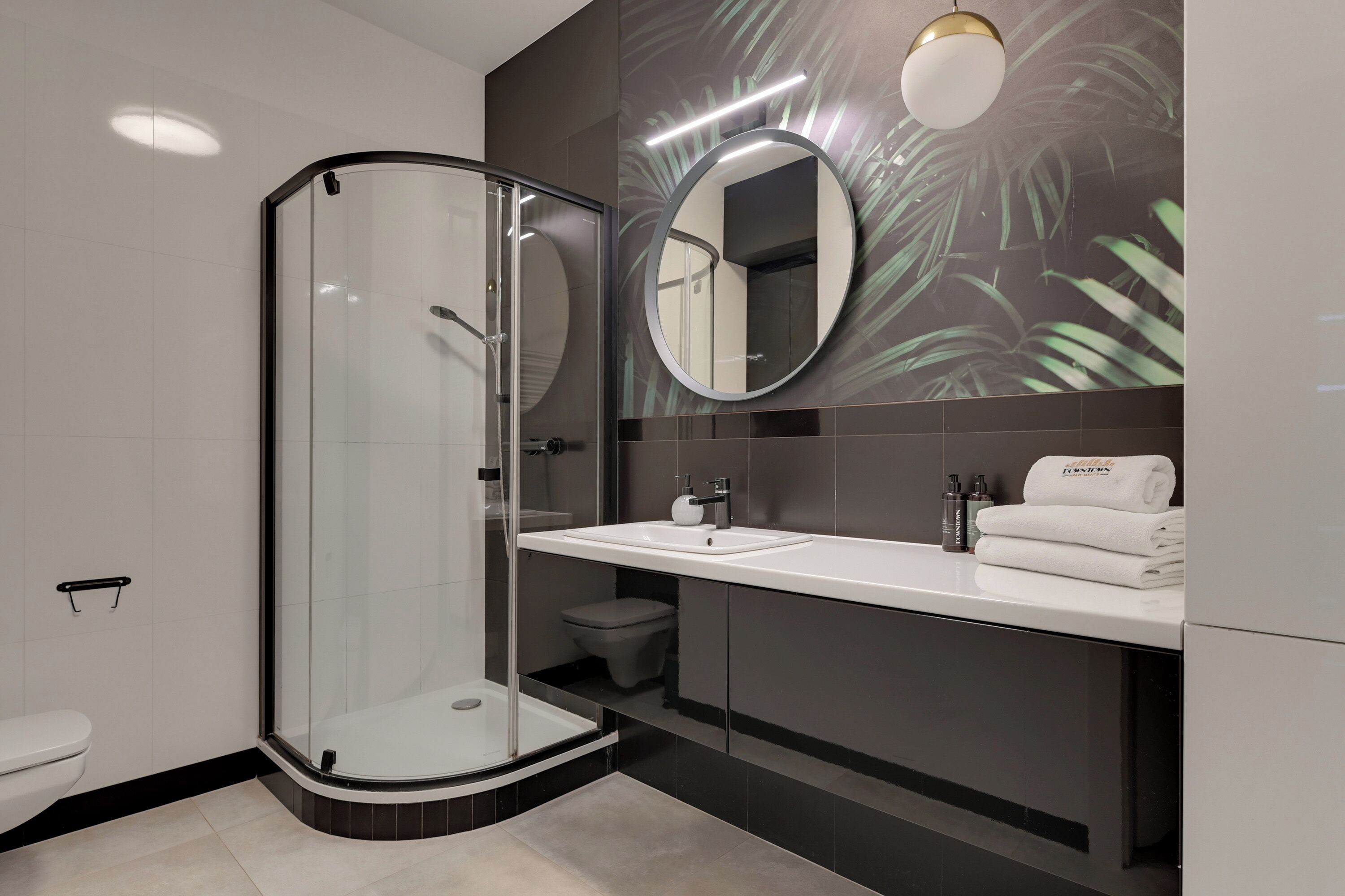A modern bathroom with a glass-enclosed shower, a vanity with a sink, and a mirror.
