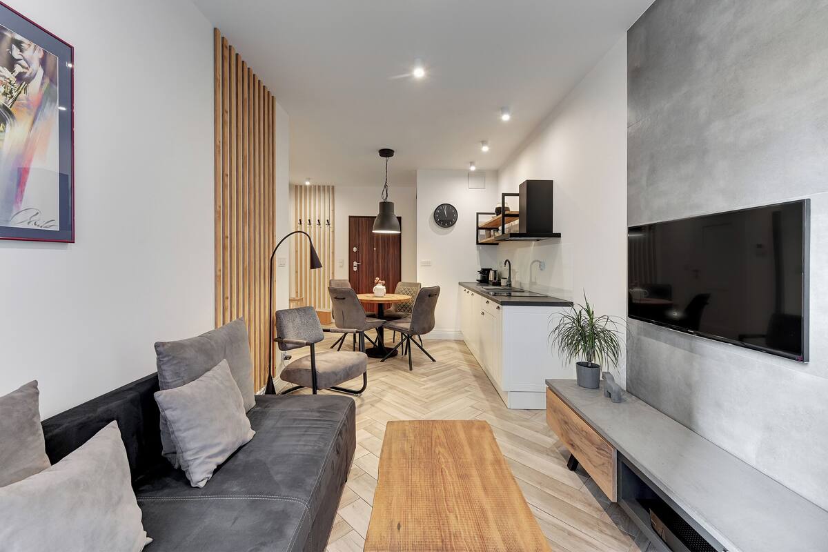 Una sala moderna con un sofá, una mesa de centro y un televisor montado en la pared.