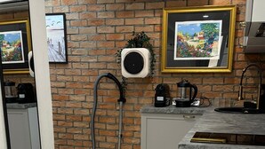 Una cocina con pared de ladrillo, un aspirador, una cafetera y cuadros en la pared.