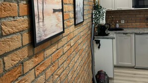 Una cocina con pared de ladrillo, dos cuadros enmarcados, una máquina de café y un microondas.