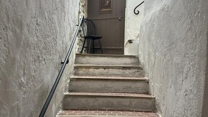 Una escalera estrecha con barandilla que conduce a una puerta con arco decorativo.