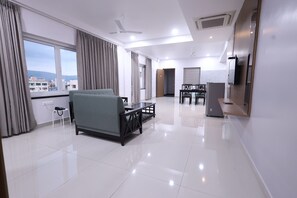 A modern hotel room with a sofa, a dining table, and a TV. - Tirupati Prime Homestay (Tirupati)