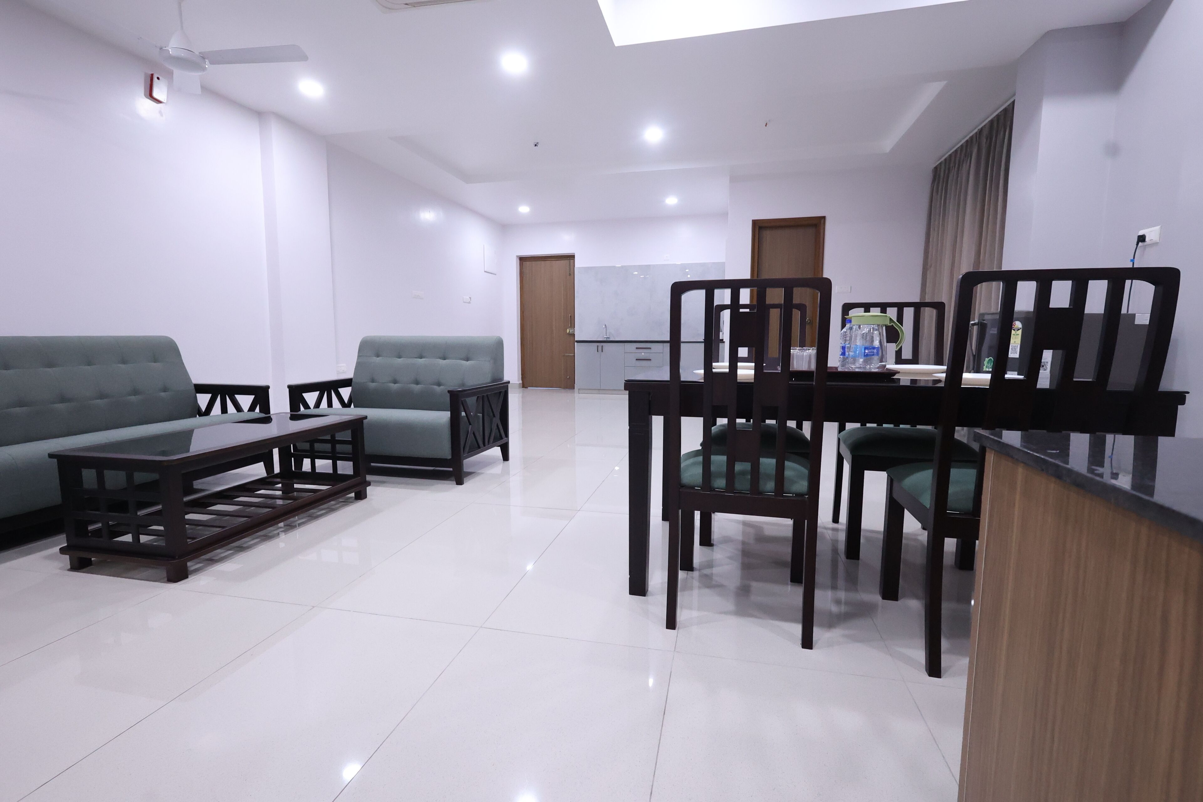 A modern living room with a sofa, coffee table, and dining area with chairs and a table.