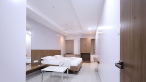 A modern hotel room with a large bed, a desk, and a wardrobe. - Tirupati Prime Homestay (Tirupati)
