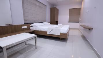 A modern hotel room with a large bed, a wooden bench, and a small table.