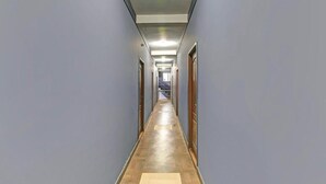 Un largo pasillo estrecho con puertas de madera a ambos lados y suelo de madera.
