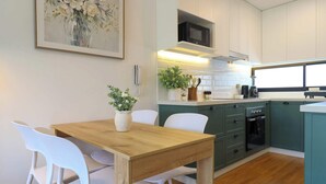 A modern kitchen with white cabinets, a wooden table, and white chairs. - w* | Cozy 1BR w/ Balcony in San Isidro (Lima)