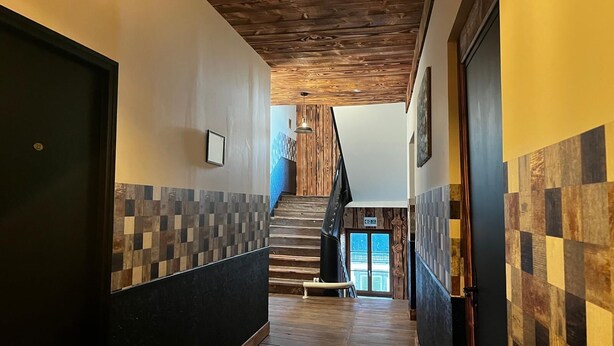 A hallway with a wooden staircase, tiled walls, and a door on the left. - prestigieuse résidence - parking (Bellac)