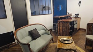 A living room with a sofa, a coffee table, and a dining area with a wooden table and chairs. - prestigieuse résidence - parking (Bellac)