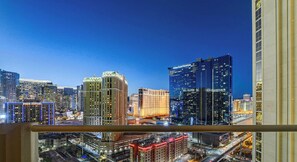 A cityscape at dusk with illuminated buildings, including a hotel with a sign. - MGM Signature- Patio Strip View Jacuzzi Studio (Las Vegas)