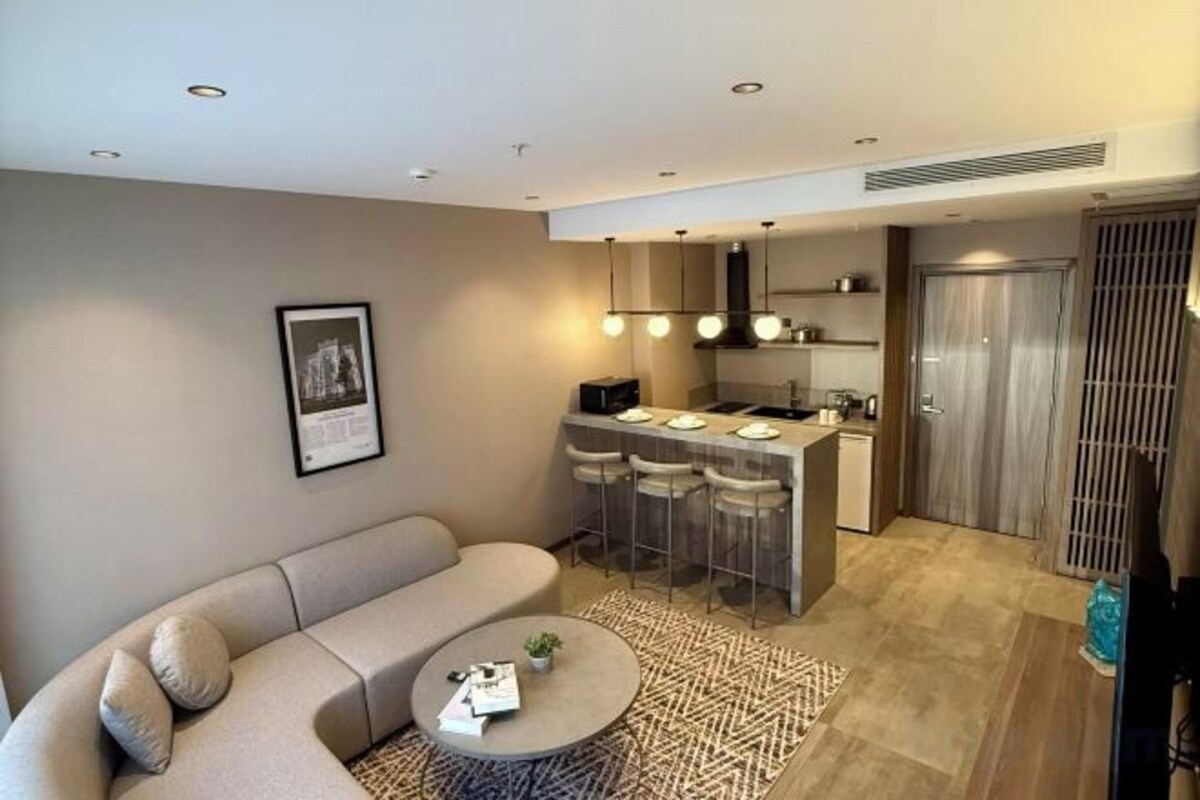 Una sala moderna con un sofá, una mesa de centro y una zona de cocina con barra.