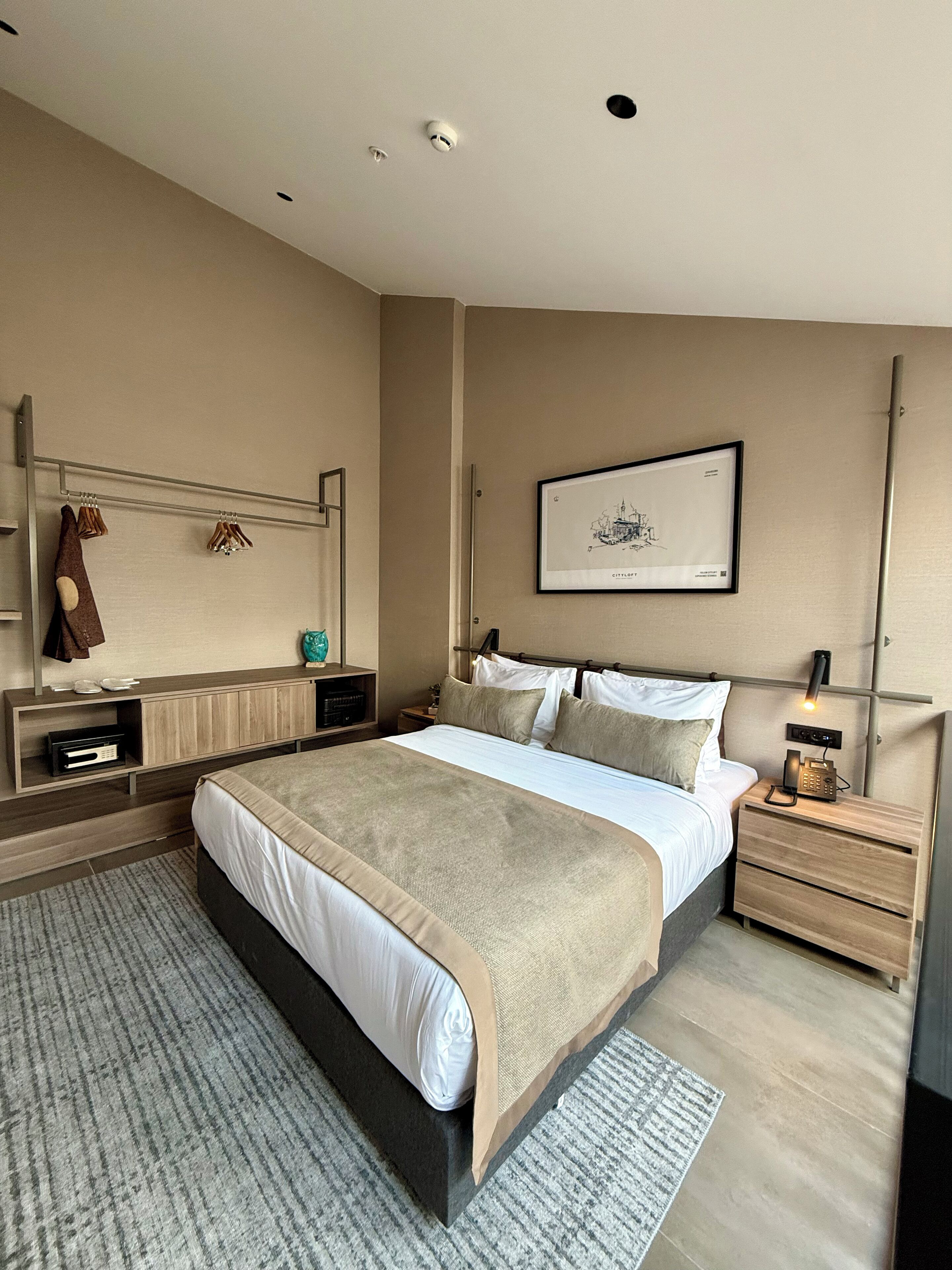 A modern bedroom with a large bed, bedside tables, a mirror, and a framed picture on the wall.
