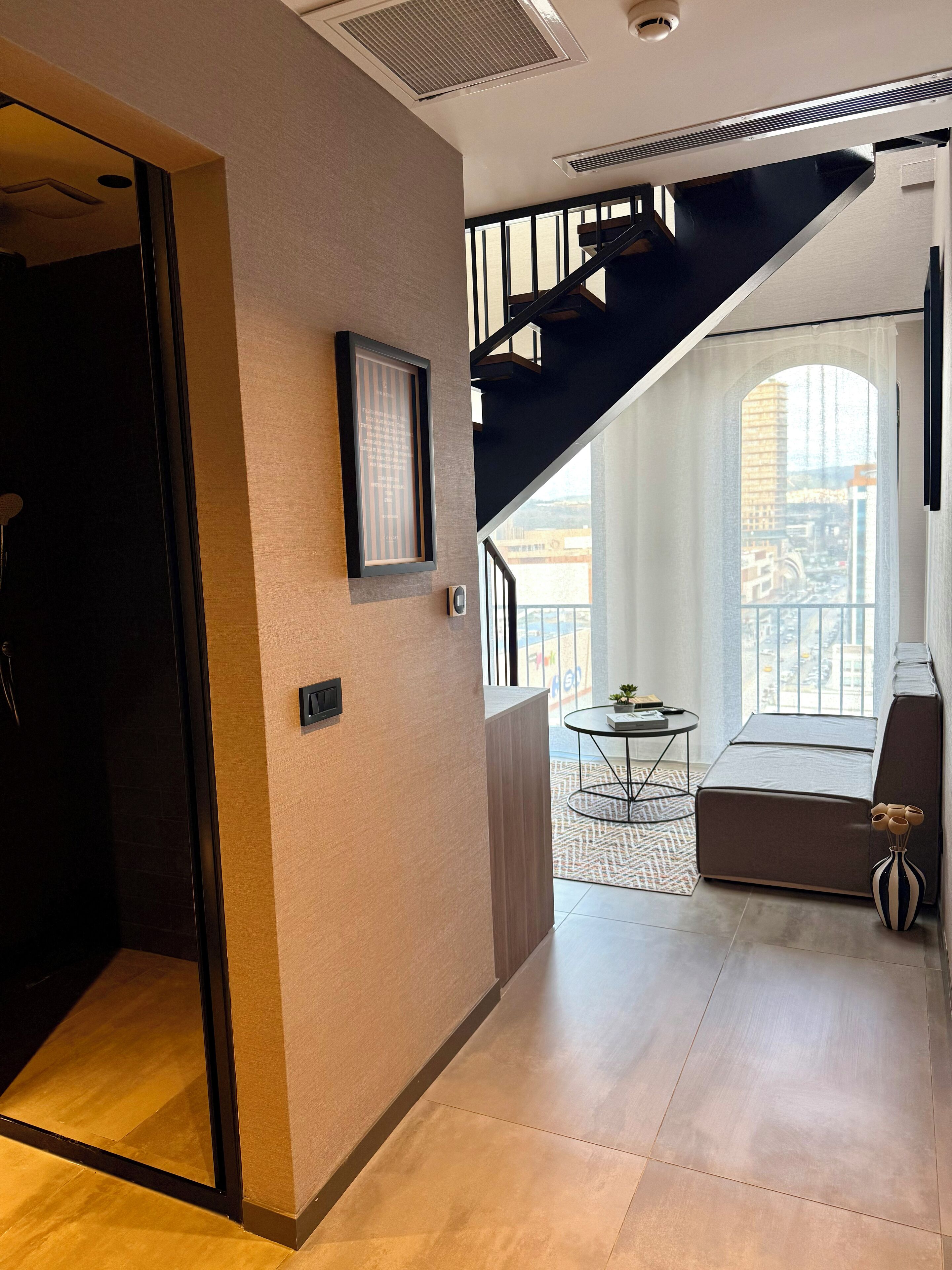 A modern interior with a staircase, a framed picture, and a balcony with a view.