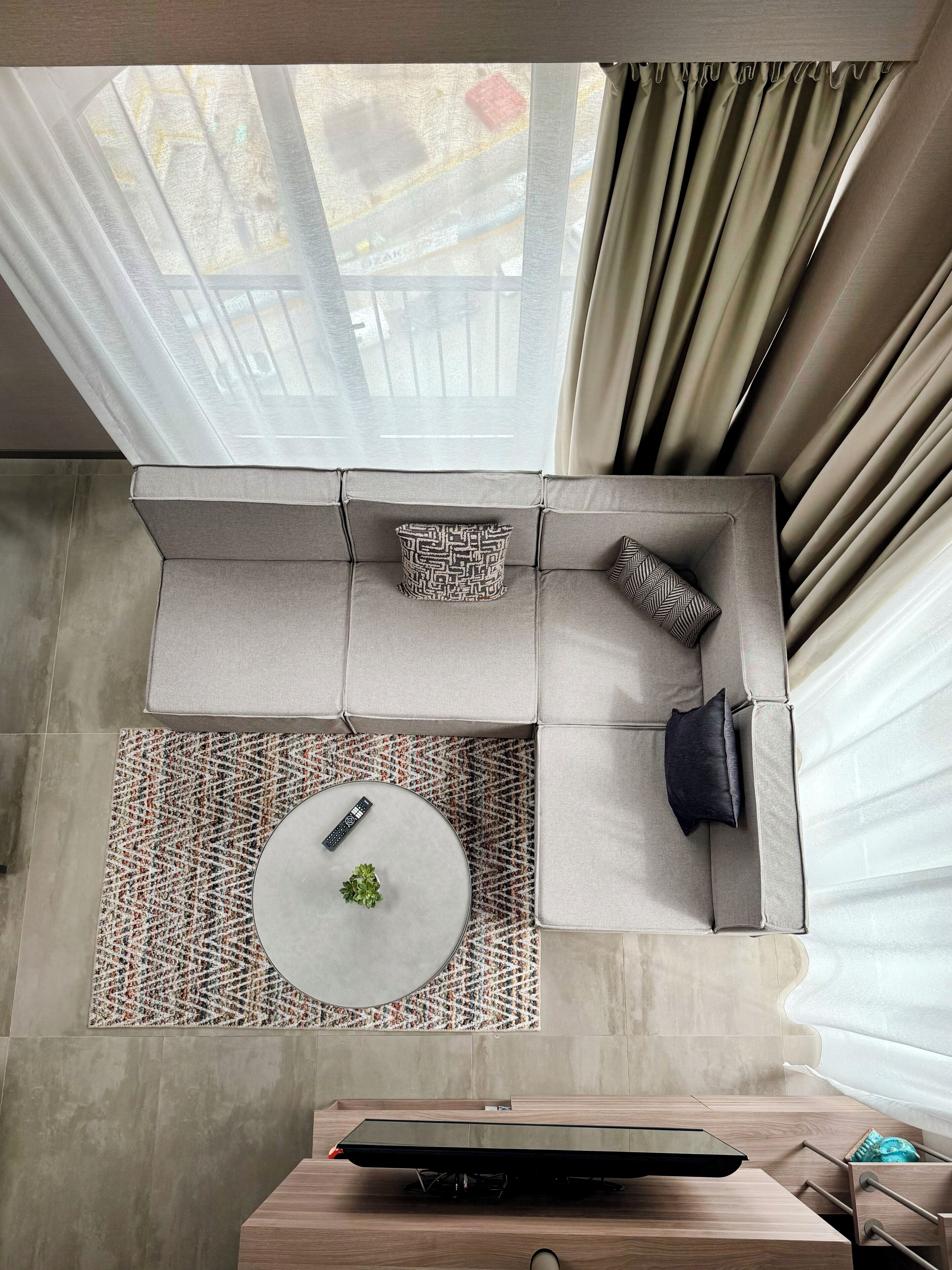 Un salon moderne avec un canapé d’angle, une table basse ronde et un téléviseur à écran plat.