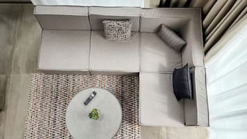 Un salon moderne avec un canapé d’angle, une table basse ronde et un téléviseur à écran plat.