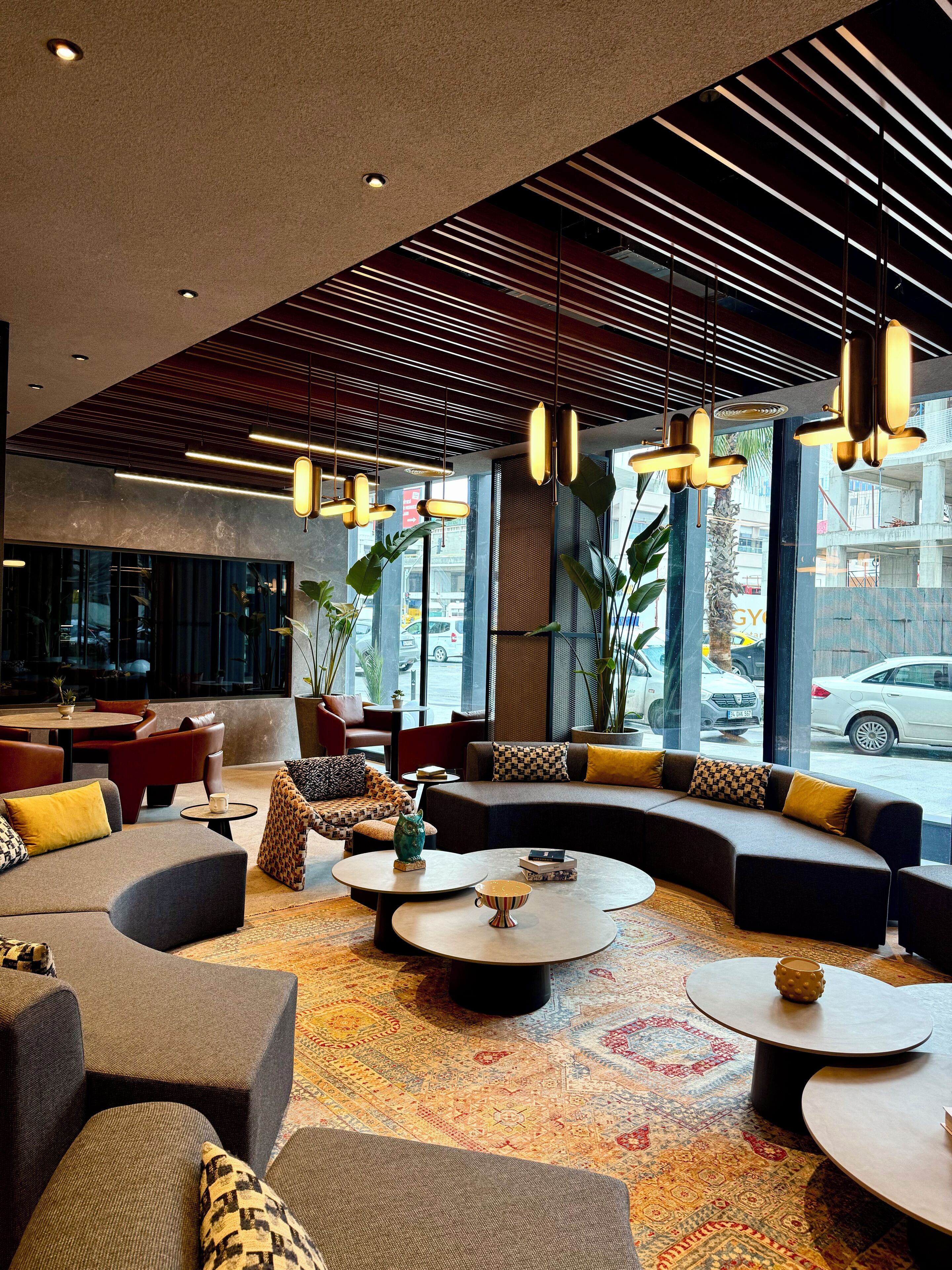 A modern lounge area with sofas, round tables, and hanging pendant lights.