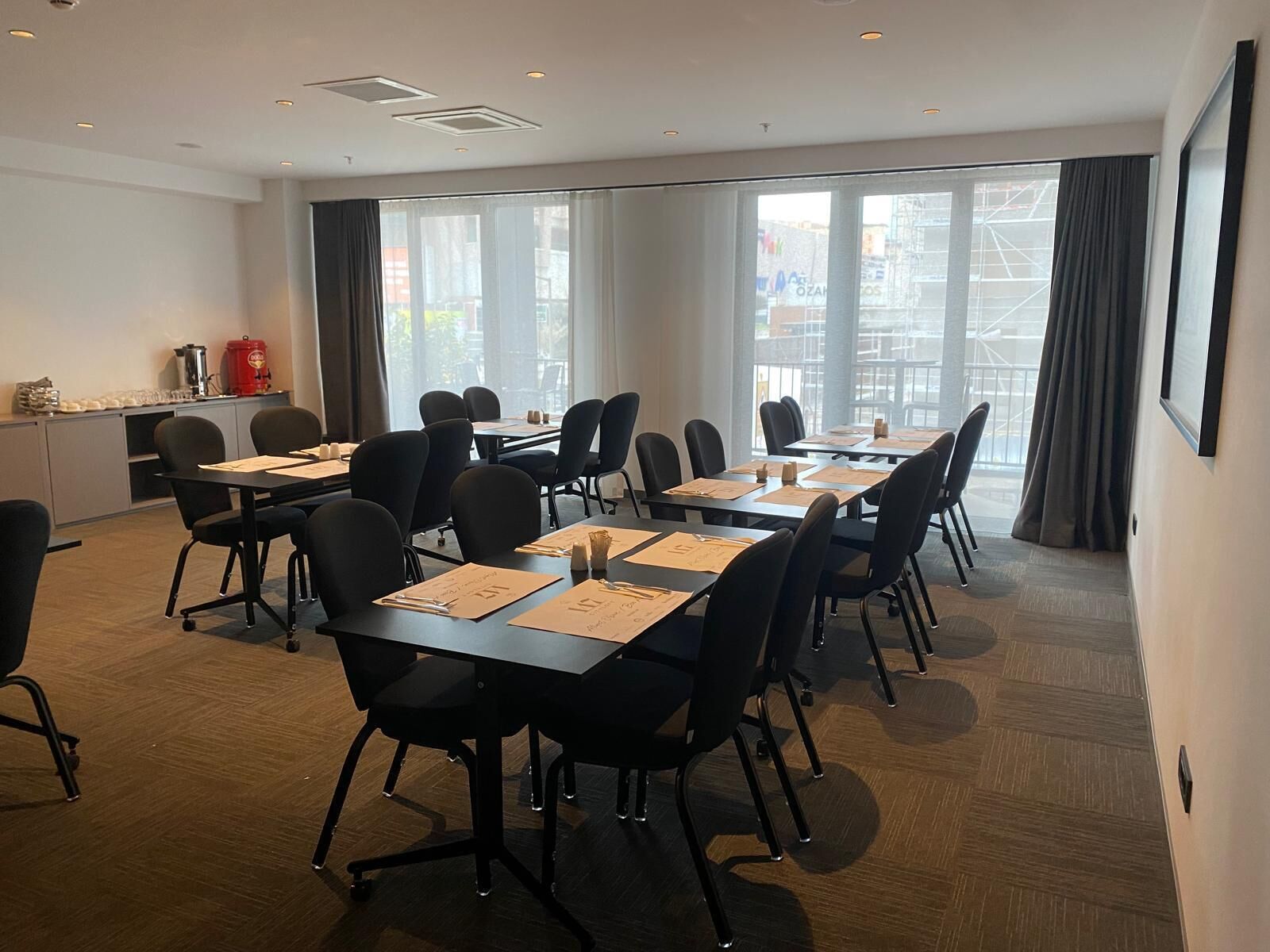 A conference room with tables, chairs, and a kitchenette area.