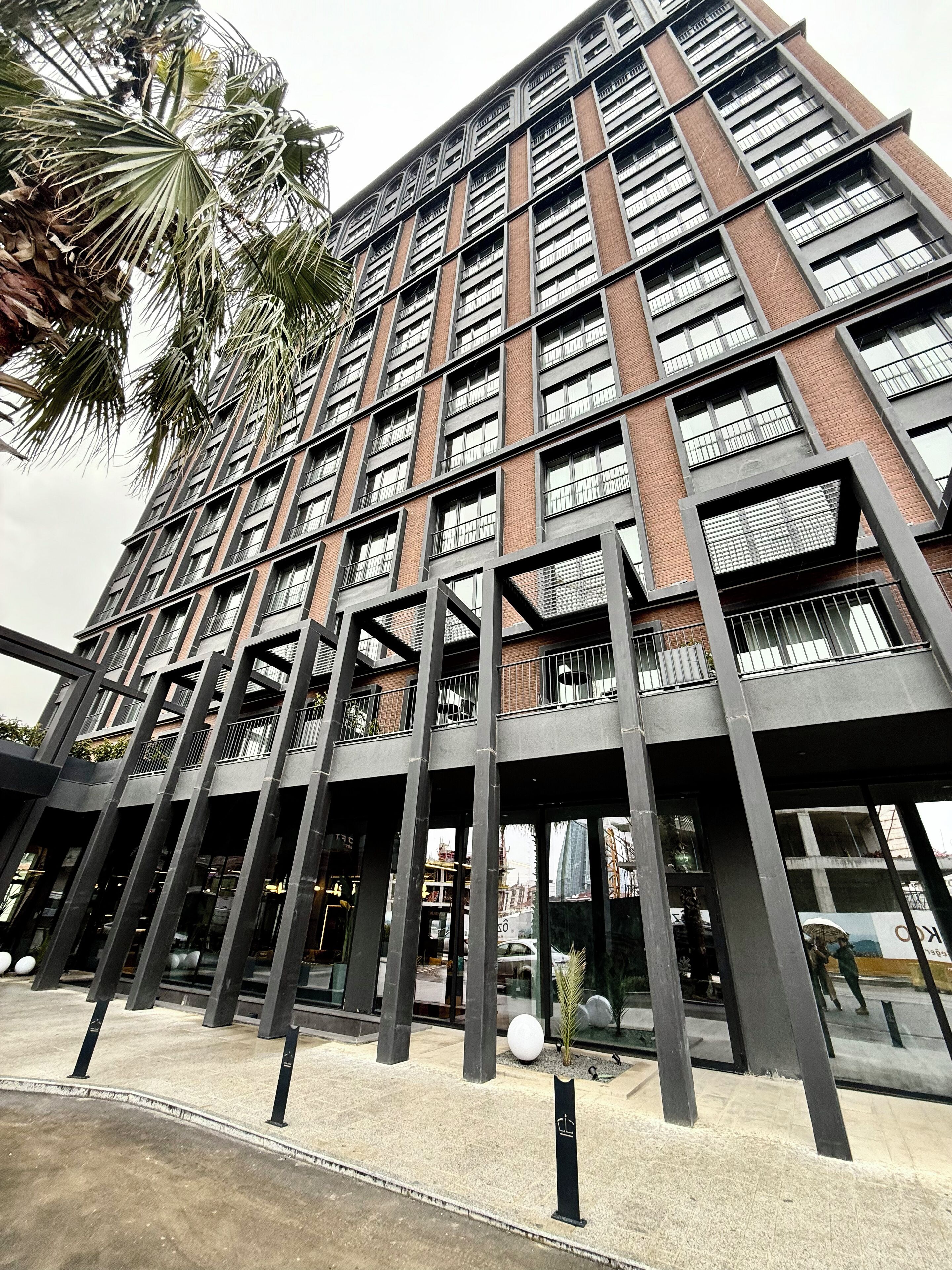 A modern building with a grid of windows and balconies, featuring a mix of brick and metal construction.