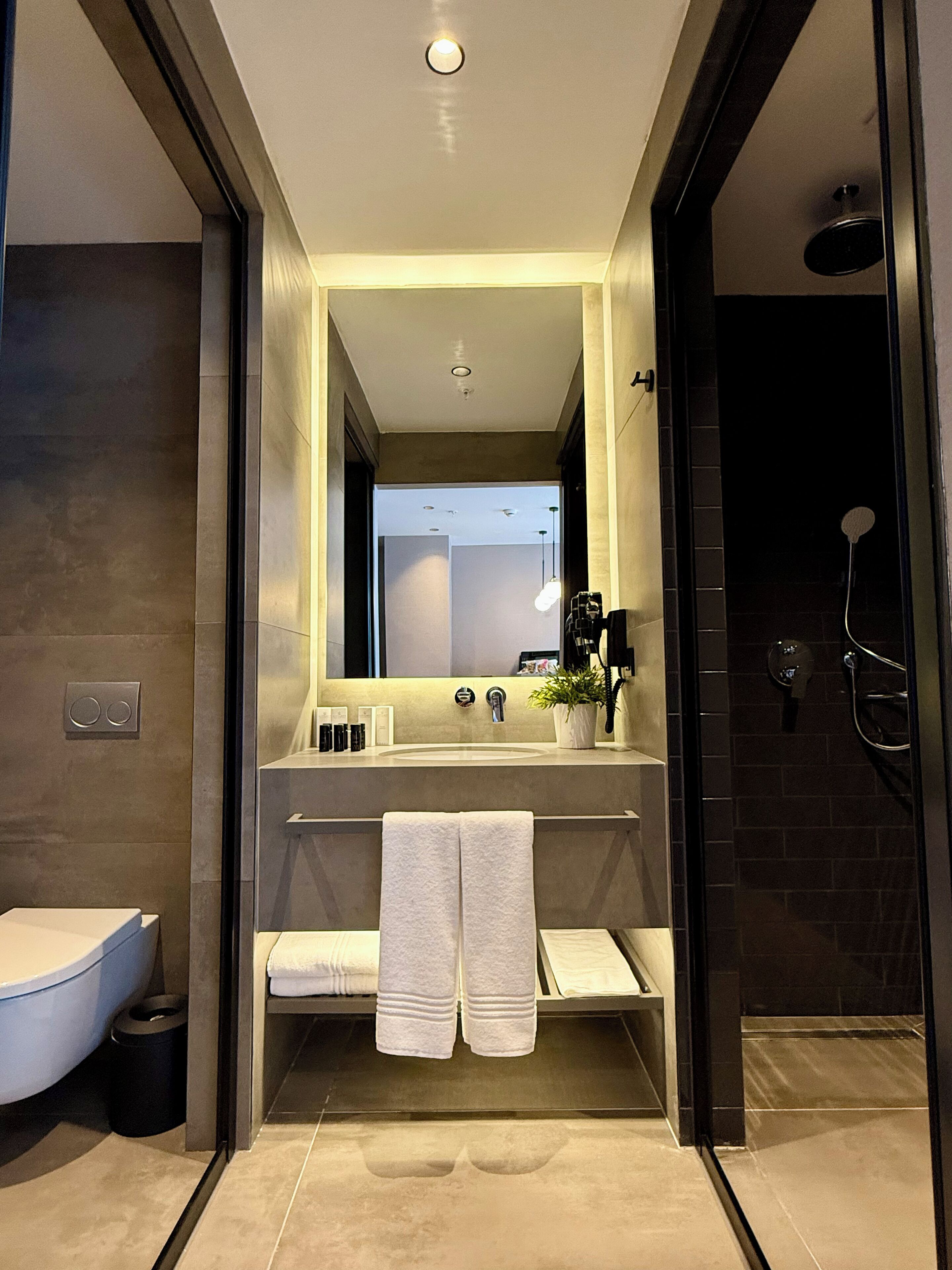 Un baño moderno con un espejo grande, un lavamanos y una ducha.