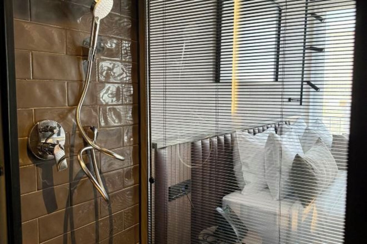 Un bagno con doccia, parete rivestita in piastrelle e finestra con persiane.