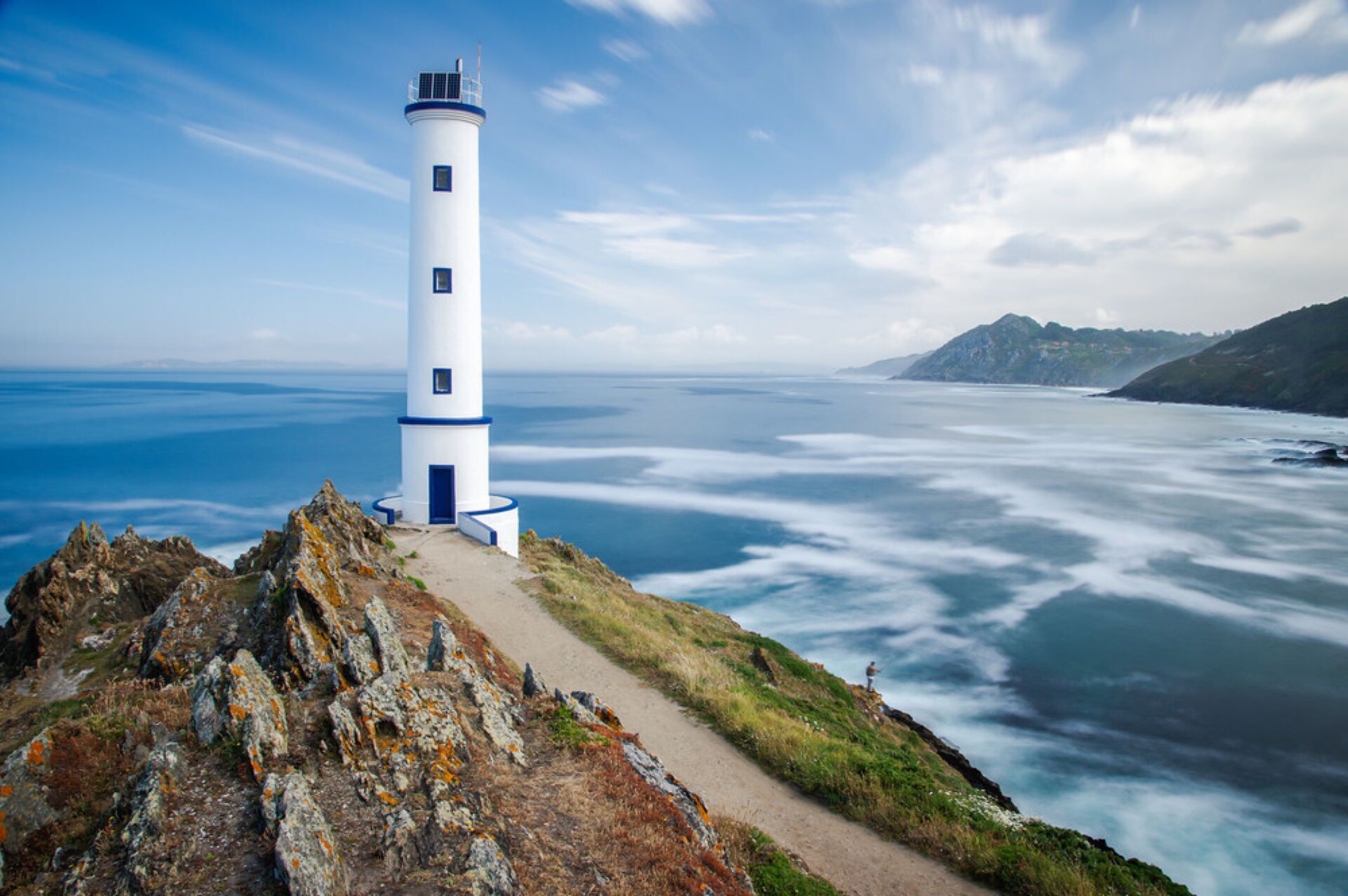 A lighthouse on a rocky cliff overlooking a vast ocean.
