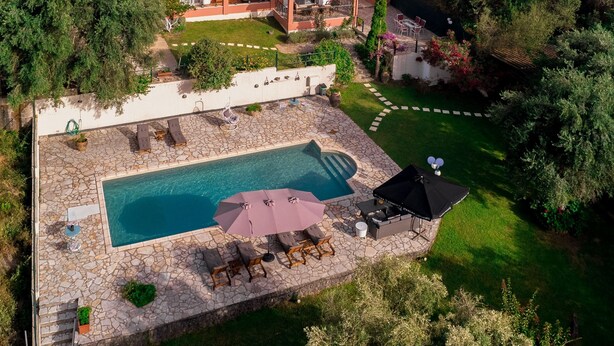 Une maison à plusieurs étages dotée d’une piscine, d’un espace salon extérieur et d’un jardin.