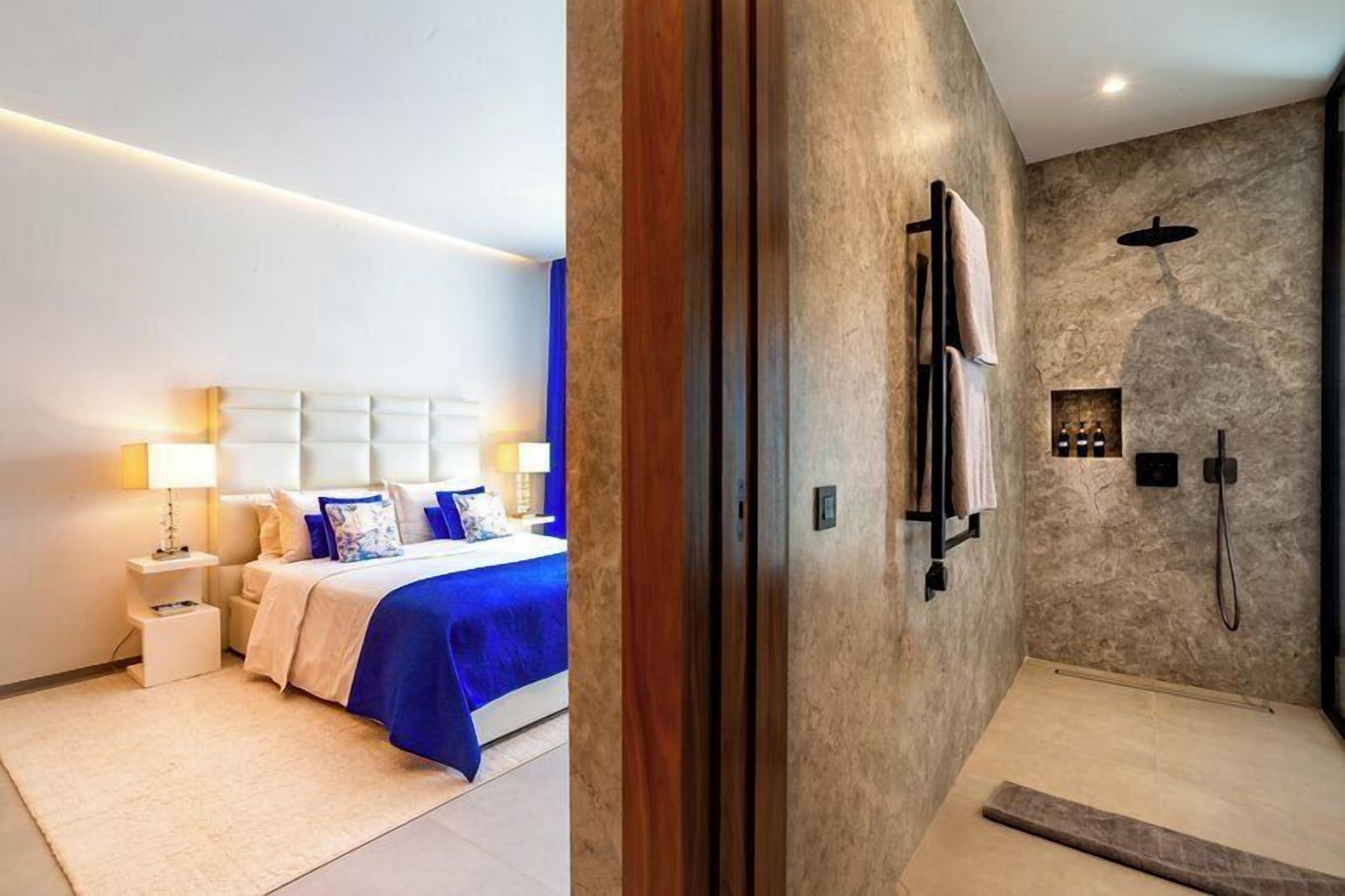 A bedroom with a bed, nightstands, and a bathroom with a shower.