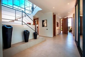 A modern interior with a staircase, a hallway, and a large window.